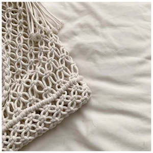 Macro detail of beige handmade macrame bag showing intricate woven knots and fringe