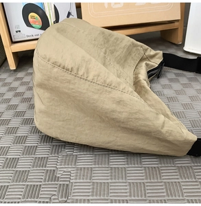Close-up of the beige nylon dumpling bag showing pleated fabric texture and black strap