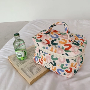 Détail d'une trousse de maquillage matelassée avec motifs colorés et double fermeture éclair