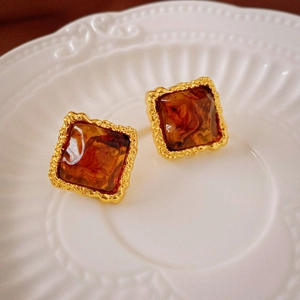 Macro view of vintage square amber resin earrings with textured gold metallic frames