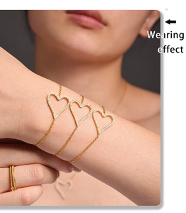 Close-up of heart-shaped gold bracelets with sparkling white zircons on a model's wrist