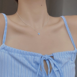 Detail of S925 silver necklace featuring a rainbow heart pendant on the model's collarbone