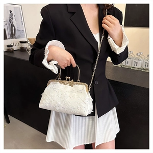 Detail of white lace shell bag with 3D floral embroidery, sequins, and gold metal handle