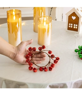 Close-up of a handmade red metal bell wreath decoration held in hand for home decor