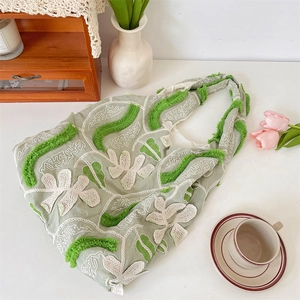 Détails de broderie florale en dentelle et textures sur un sac cabas vert clair esthétique