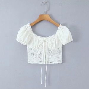 Détail du haut court blanc avec manches bouffantes, dentelle et encolure carrée nouée