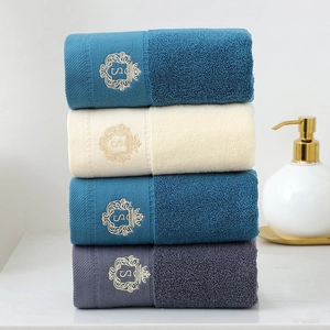 Stack of four absorbent thick cotton towels in blue, beige, and grey with S embroidery