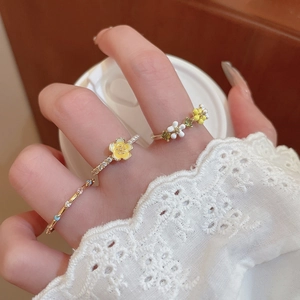 Detail of floral rings with yellow and white enamel petals and rhinestones on gold band