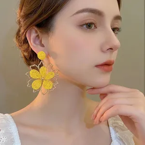 Bohemian large yellow woven flower earrings with gold metallic edges on model