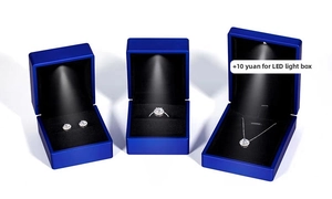 Navy blue jewelry box set with integrated LED spotlight highlighting a moissanite necklace