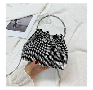 Detail of black rhinestone bucket bag with silver metal handles and chain strap