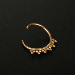 Detailed macro view of a golden 316L stainless steel nose ring with tiny spherical beads