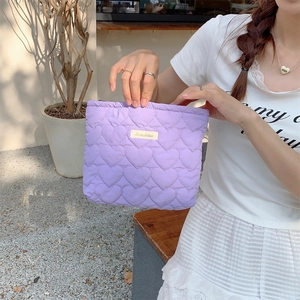 Close-up of a lavender quilted heart pouch held by a model in soft outdoor lighting