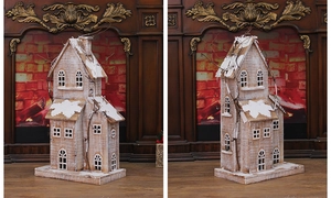 Close-up of wooden snow house ornament with distressed white finish and branch details