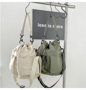 Detail view of nylon drawstring bucket bags in beige and olive green colors