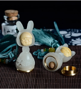 Macro detail of sandalwood rabbit diffuser with white jade-like body and green tassel