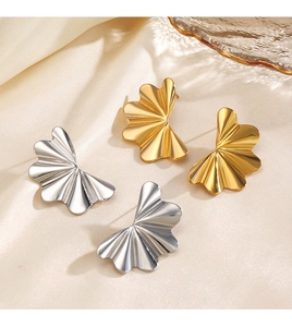 Vue détaillée des boucles d'oreilles vagues dorées et argentées sur satin beige doux