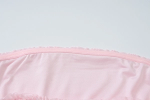 Close-up of pink layered dress fabric with delicate ruffles and precise stitching details