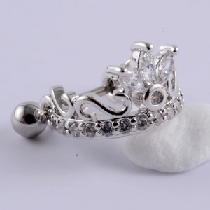 Macro detail of crown shaped belly ring with cubic zirconia stones on white stone base