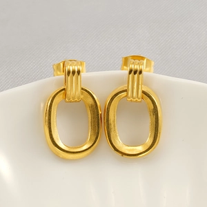 Detailed macro view of vintage gold geometric earrings hanging on a white ceramic plate