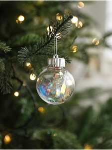 Macro shot of iridescent mesh Christmas ball hanging on a tree with festive bokeh lighting