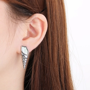 Macro detail of silver conch shell earring with white shell inlay and zircon accents
