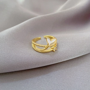 Macro shot of gold mermaid tail ring with a small zircon on grey silk fabric
