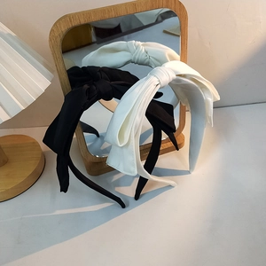 Close-up of elegant double-layered bow headbands in black and white fabric texture