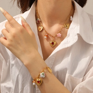 Detailed shot of gold-plated jewelry set with heart, mushroom, and floral charms