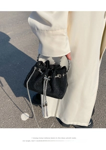 Detail of a black mini bucket bag with sparkling rhinestones and metal chain tassels