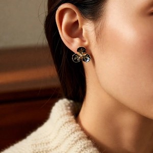 Détail de puce d'oreille fleur vintage avec émail noir et bords dorés sur l'oreille