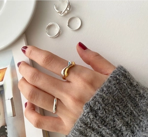 Close-up of minimalist 925 sterling silver wavy ring layered on model's hand