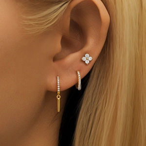 Macro side view of gold floral stud and sparkling rhinestone hoop earrings set