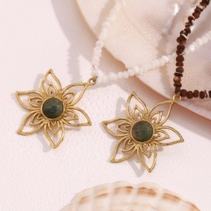 Detail of 18K gold flower pendants with green stones on beaded necklaces and sea shell