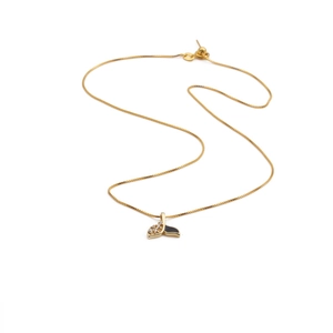 Detailed view of gold fish tail necklace with black enamel and sparkling zircon accents