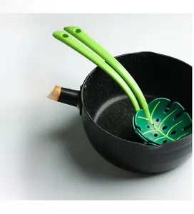 Macro detail of leaf-shaped strainer with drainage holes inside a black kitchen pot