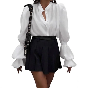 Close-up of elegant white blouse with ruffle details and pleated skirt on a model