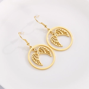 Detail shot of golden circular angel wing earrings with crystal accents on white ceramic