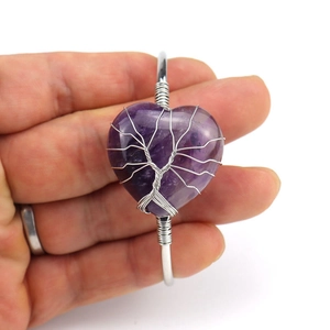 Detailed close-up of heart-shaped amethyst bracelet with silver wire-wrapped tree of life