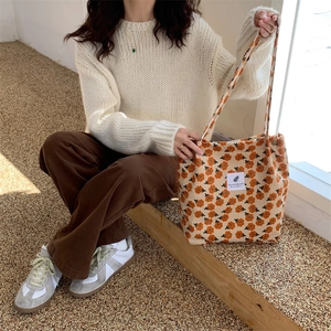 Close-up of beige corduroy tote with orange floral pattern and decorative fabric label