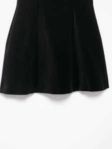 Gros plan détaillé de la texture en velours noir sur l'ourlet d'une mini robe plissée