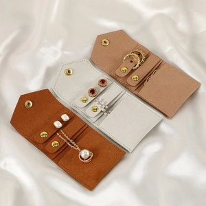 Detail of portable suede jewelry pouches in brown and grey with secure snap closures