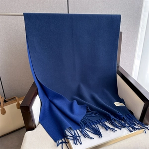 Close-up of dark blue cashmere feel scarf with soft tassels and woven brand label detail