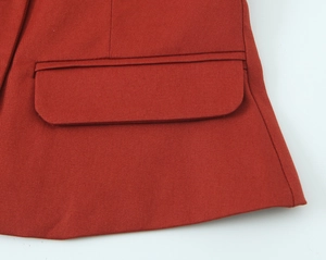 Detail shot of red blazer pocket featuring woven texture and refined stitching