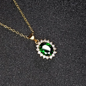 Classic green emerald pendant necklace with halo crystal setting on a gold chain