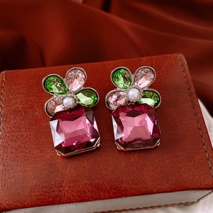 Detail of flower earrings with colorful gems and pearls on a vintage brown box