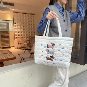 Detailed view of white quilted handbag with cute dog embroidery and nice text slogan