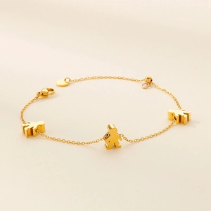 Detailed macro view of a gold stainless steel bracelet with three 3D figure pendants