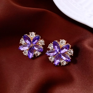 Detail of purple flower stud earrings with crystals on brown silk background