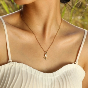 Detailed close-up of a golden tulip zircon pendant on a necklace worn by a model